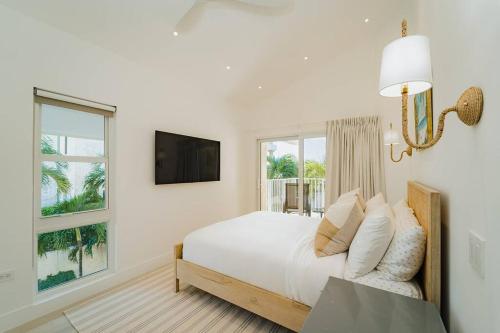 una camera bianca con letto e TV di Seven Mile Beach Luxury 3BR Condo- Best Rates! a George Town