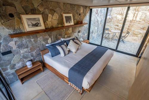 Un dormitorio con una cama en una pared de piedra. en Casa Zilin - Cuatro Cuatros, en Valle de Guadalupe