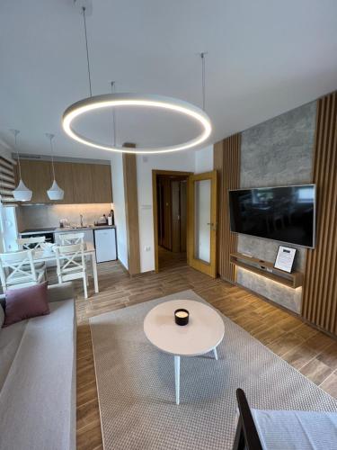 a living room with a table and a tv at Verde Apartman Sokobanja in Soko Banja