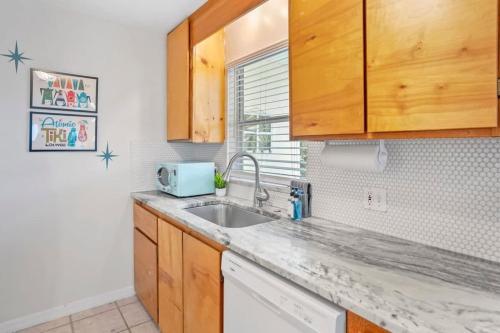 a kitchen with wooden cabinets and a sink at The Atomic Burst 50s Mid Century Apt in the Heart of St Aug Beach Steps to Sand Bites and Drinks in Saint Augustine