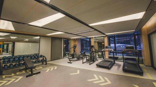 a gym with treadmills and ellipticals in a building at MUSTEL Hotel Guangzhou Nansha in Guangzhou
