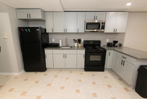 uma cozinha com armários brancos e um frigorífico preto em Bright & Cozy 2-Bed Apt mins to NYC em Jersey City