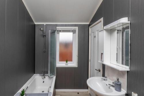 a bathroom with a sink and a bath tub and a window at Family Luxury York Cabin Retreat with hot tub in York