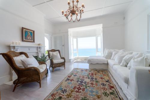 a living room with a white couch and a chandelier at Kalimera Beach House in Mossel Bay