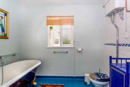 a white bathroom with a tub and a toilet at Off grid chalet . HOT TUB & SAUNA. Kid friendly. in Langport
