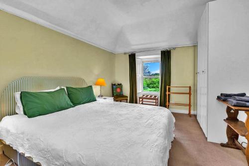 Un dormitorio con una cama con almohadas verdes y una ventana en Finest Retreats - The West Wing at The Mill House en East Linton