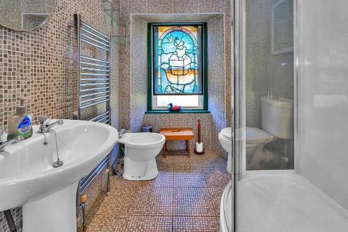 bagno con lavandino, servizi igienici e finestra istoriata. di Finest Retreats - The West Wing at The Mill House a East Linton