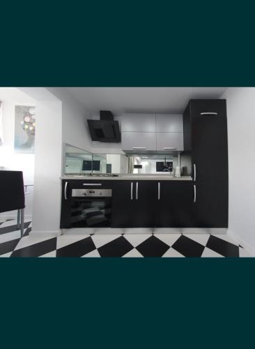 cocina con armarios negros y suelo a cuadros en ONYX Apartament, en Brăila