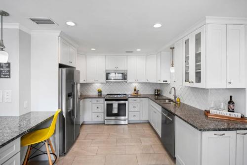 a white kitchen with white cabinets and a yellow chair at Onyx House King Size Beds Bikes Games Wine in St. Augustine