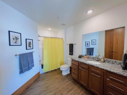 baño con lavabo y cortina de ducha amarilla en 3BR Disney Apt at The Grand Castle, en Grandville