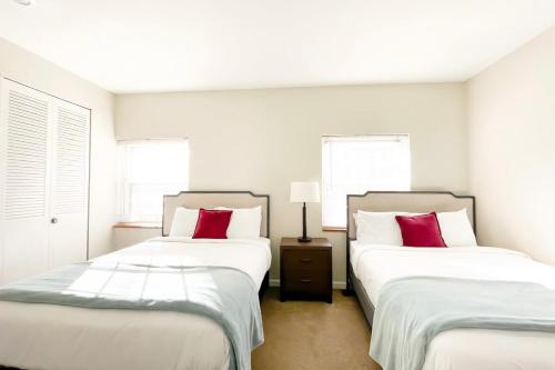 two beds in a white room with red pillows at 2BR and 2BA Beer City Flat with Pool Gym and Parking in Grand Rapids