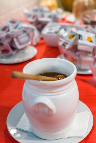a white cup of coffee on a plate with a spoon at Hotel Piroska in Bük