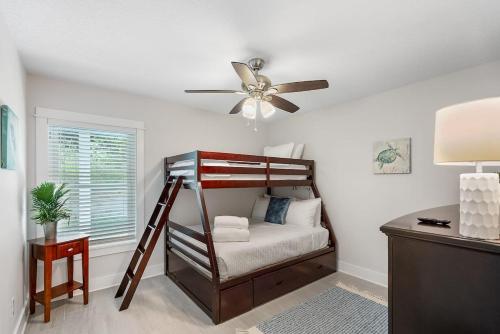 a bedroom with a bunk bed and a ceiling fan at Treetop Terrace 250 Steps to Beach Heated Swim Spa in Saint Augustine