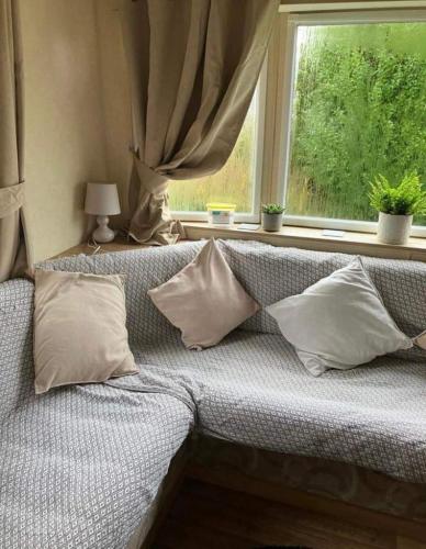 a couch sitting in front of a window with pillows at 2-Bed Caravan in Mablethorpe sea front location in Mablethorpe