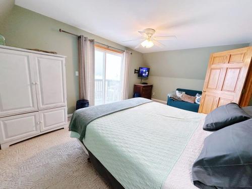 sypialnia z łóżkiem i wentylatorem sufitowym w obiekcie Beach Club of Oscoda Beach House on Lake Huron w mieście Oscoda