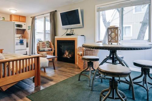 un soggiorno con tavolo e camino di Beach Club of Oscoda Garden Cottage on the Lake a Oscoda