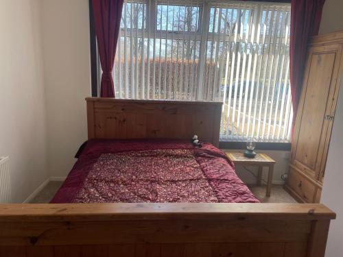 a bedroom with a wooden bed with a large window at Homestay in Glasgow