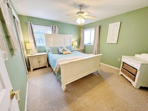 a bedroom with green walls and a bed with a fan at Beach Club of Oscoda - The Lakeshore Cottage in Oscoda