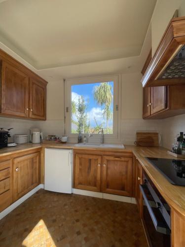 a kitchen with wooden cabinets and a window at Villa Blanche in Agon-Coutainville
