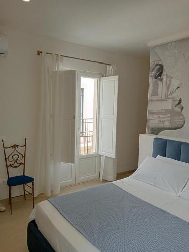 a bedroom with a bed and a chair and a window at Vicol8Netino in Noto