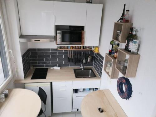 une petite cuisine avec un évier et un micro-ondes dans l'établissement Studio avec parking privé et métro, à Boulogne-Billancourt