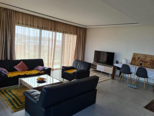 a living room with a couch and a table and a tv at Appartement moderne vue sur mer in Essaouira