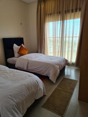 two beds in a hotel room with a window at Appartement moderne vue sur mer in Essaouira