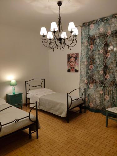 a bedroom with two beds and a chandelier at La Residenza del Cavallino in Fermo