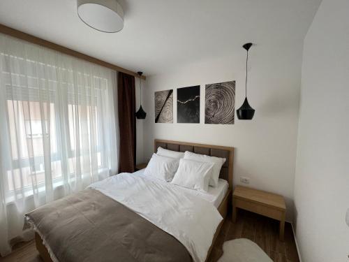 ソコバニャにあるLa Vista Apartman - Sokobanjaの白いシーツと窓のあるベッドのある寝室