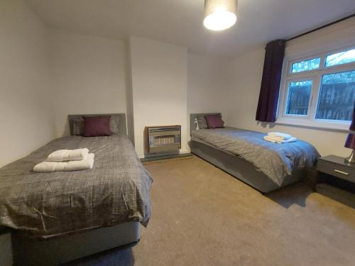 een slaapkamer met 2 bedden en een raam bij Ingledene in Wrexham