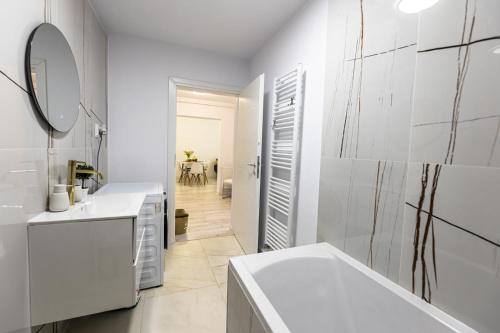 a white bathroom with a tub and a mirror at West Marina Aparthotel Cluj in Floreşti