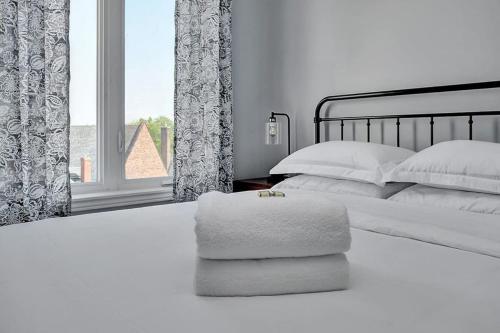 a white bedroom with a bed with pillows and a window at High-end condo downtown Kingston near RMC Queens in Kingston