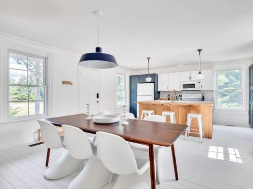 a white kitchen with a wooden table and white chairs at The Gem - Beautiful farmhouse with hot tub in West Lake