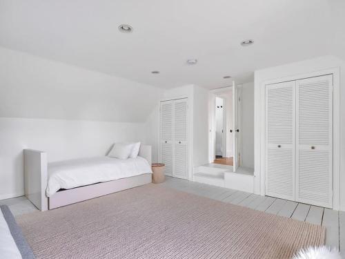 a bedroom with white walls and a bed with a rug at The Gem - Beautiful farmhouse with hot tub in West Lake