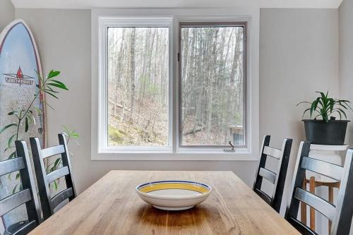 a dining room with a wooden table and two windows at La Hacienda - Edelweiss après-ski - wooded escape in Val des Monts