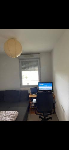 Zimmer mit einem Schreibtisch, einem Computer und einem Sofa in der Unterkunft Chambre dans un Appartement avec Parking privé in Toulouse