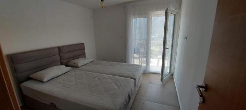 une chambre avec un lit et une grande fenêtre dans l'établissement Biserni Apartman 1, à Kotor