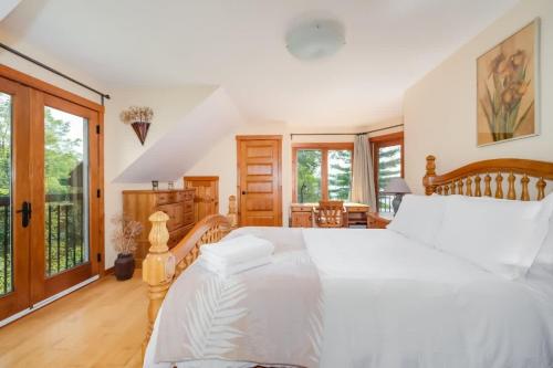 - une chambre avec un grand lit blanc et des fenêtres dans l'établissement Sunset Cove Waterfront nature retreat with bunkie, à Westport