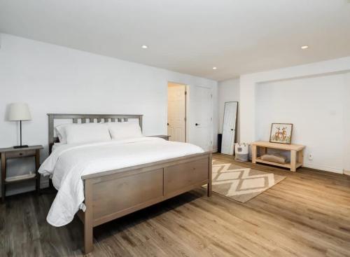 a white bedroom with a large bed and wooden floors at Waterfront open concept dream cottage with hot tub in Portland