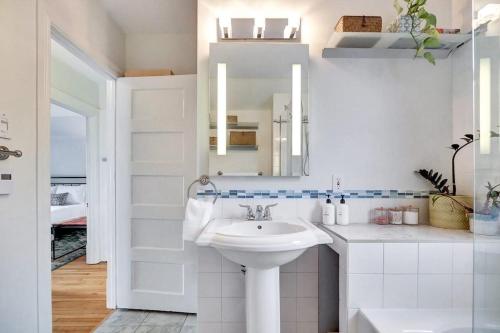 a white bathroom with a sink and a mirror at Century home by river hot tub & parking in Ottawa