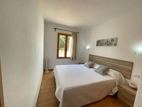 a bedroom with a bed and a window at Mestral -Apartamento con piscina junto la playa in Arenal d'en Castell