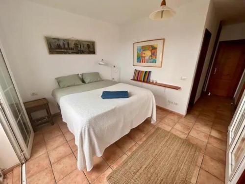 埃爾梅達諾的住宿－Integral Coliving Surf Yoga House，一间卧室配有一张白色的床,上面有蓝色的毛巾