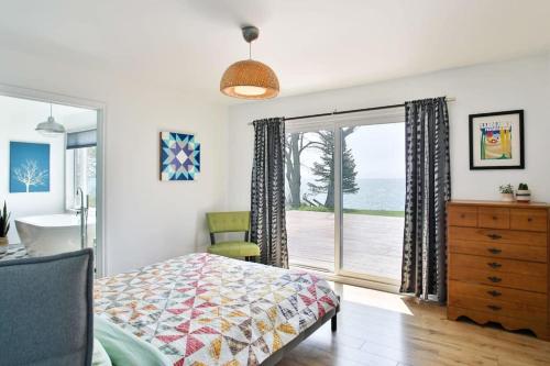 a bedroom with a bed and a sliding glass door at Lakeside PEC: Beautiful Waterfront & Patio in Wellington