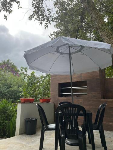 une table avec deux chaises et un parasol dans l'établissement Casa Uno chácara, à Suzano