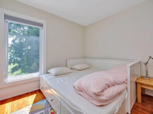 a white bedroom with a bed with a window at Wind & Waves - Wellington waterfront with Satellite TV & fire pit in Wellington
