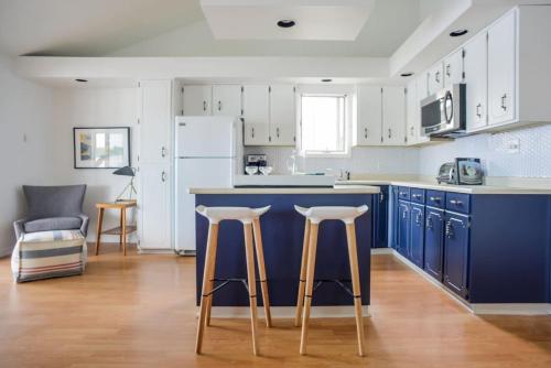 a kitchen with a blue island and two bar stools at The Verne: Beautiful Waterfront Escape by Picton in Picton