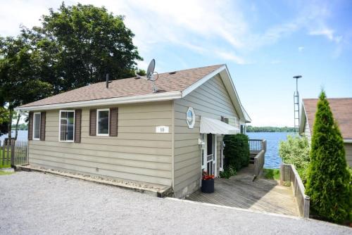 a small house with a porch next to a body of water at The Verne: Beautiful Waterfront Escape by Picton in Picton