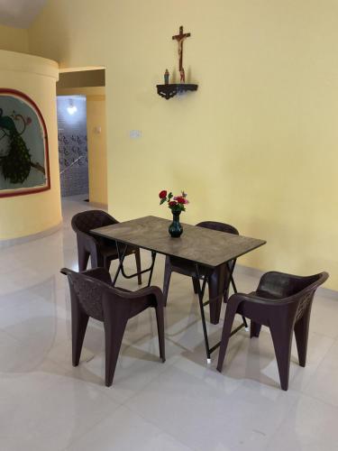 a table and chairs with a vase of flowers on it at Grace Homestay in Benaulim