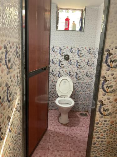a bathroom with a toilet with a window and a mirror at Grace Homestay in Benaulim