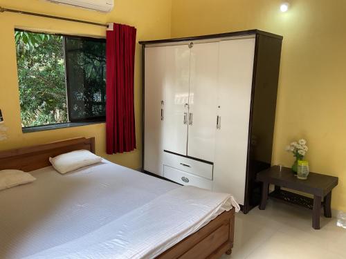 a bedroom with a bed and a cabinet and a table at Grace Air-conditioned Cool Homestay in Benaulim